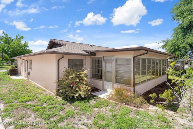 10820 Hachita Dr, Port Richey, FL 34668 - back of property with a sunroom, stucco siding, cooling unit, and a shingled roof
