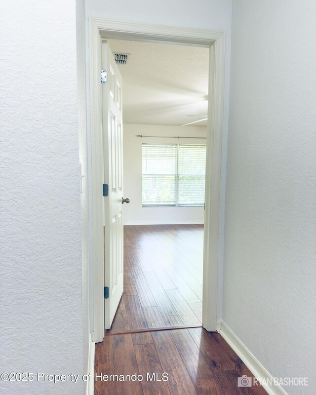 3095 Coronet Ct, Spring Hill, FL 34609 - hall featuring dark wood-style flooring, a textured wall, and baseboards