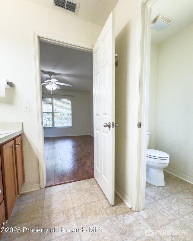 3095 Coronet Ct, Spring Hill, FL 34609 - bathroom with toilet, vanity, baseboards, and a ceiling fan