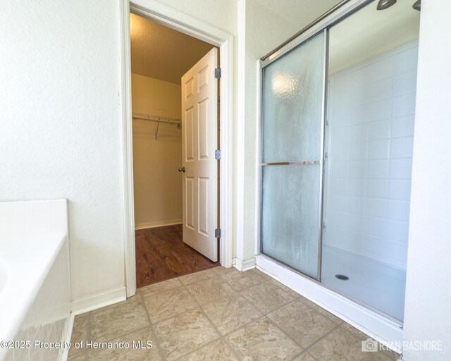 3095 Coronet Ct, Spring Hill, FL 34609 - full bathroom with a stall shower, a spacious closet, baseboards, and a bath