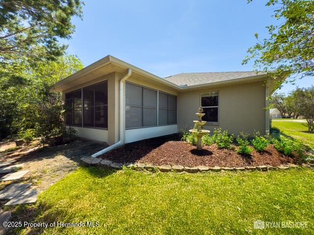 3095 Coronet Ct, Spring Hill, FL 34609 - view of home's exterior with a sunroom, stucco siding, and a yard