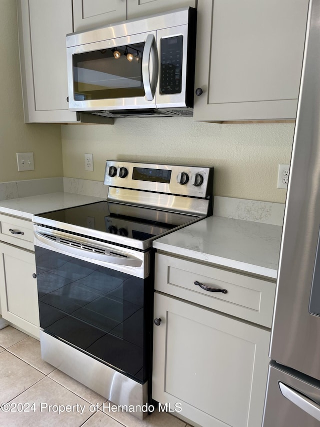 10448 Canary Ave, Weeki Wachee, FL 34613 - kitchen with stainless steel appliances, light tile patterned flooring, and white cabinets