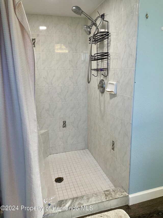 10448 Canary Ave, Weeki Wachee, FL 34613 - bathroom featuring a tile shower and baseboards