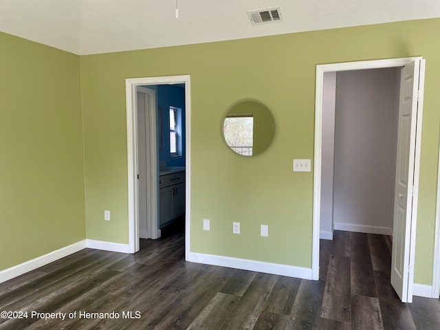 10448 Canary Ave, Weeki Wachee, FL 34613 - unfurnished bedroom featuring dark wood-style flooring, baseboards, and connected bathroom