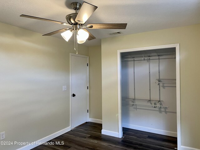 10448 Canary Ave, Weeki Wachee, FL 34613 - unfurnished bedroom with dark wood-style floors, a closet, baseboards, a ceiling fan, and a textured ceiling