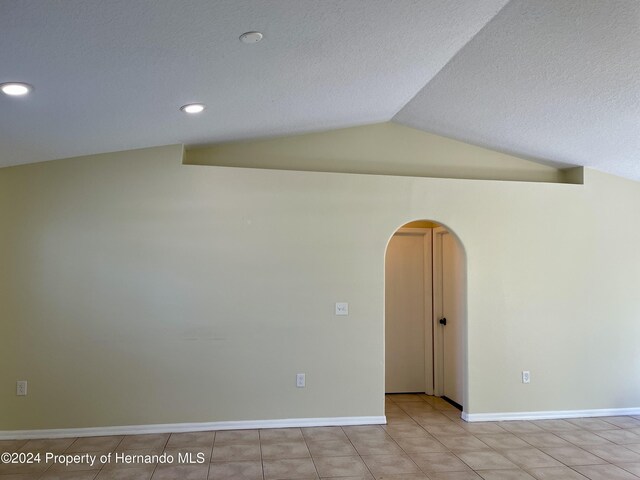 10448 Canary Ave, Weeki Wachee, FL 34613 - spare room with arched walkways, lofted ceiling, a textured ceiling, recessed lighting, and baseboards