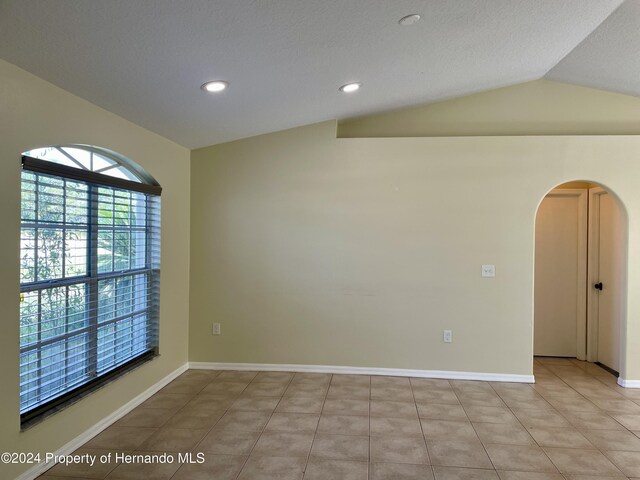 10448 Canary Ave, Weeki Wachee, FL 34613 - empty room featuring arched walkways, lofted ceiling, recessed lighting, light tile patterned floors, and a textured ceiling