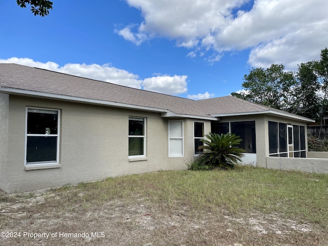 10448 Canary Ave, Weeki Wachee, FL 34613 - view of property exterior with a sunroom, stucco siding, and a shingled roof