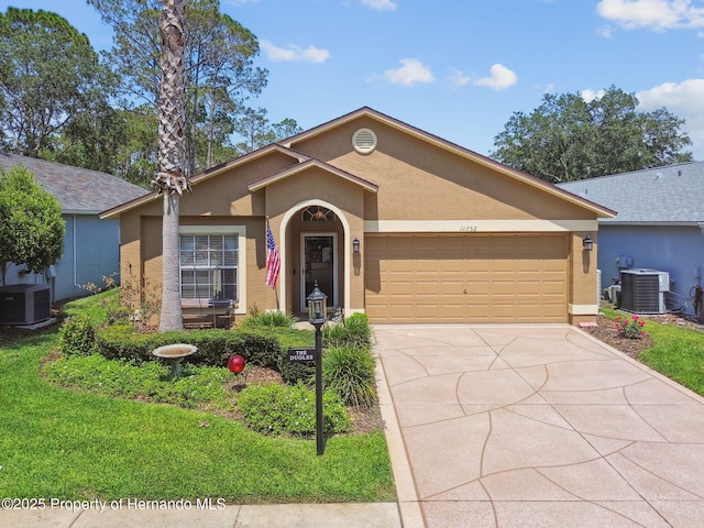 11752 Wheatfield Loop, Hudson, FL 34667 - ranch-style house featuring central air condition unit, stucco siding, concrete driveway, and a garage