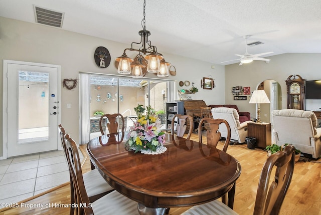 11752 Wheatfield Loop, Hudson, FL 34667 - dining room featuring vaulted ceiling, light wood-type flooring, ceiling fan, arched walkways, and a chandelier