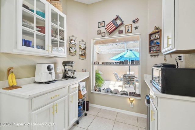 11752 Wheatfield Loop, Hudson, FL 34667 - kitchen featuring black microwave, white cabinetry, light tile patterned floors, glass insert cabinets, and baseboards