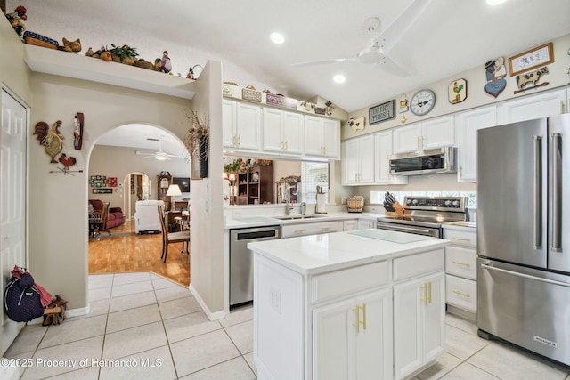 11752 Wheatfield Loop, Hudson, FL 34667 - kitchen with stainless steel appliances, ceiling fan, a center island, light tile patterned flooring, and white cabinets