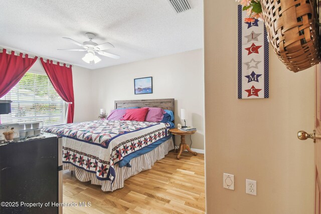 11752 Wheatfield Loop, Hudson, FL 34667 - bedroom featuring wood finished floors, a textured ceiling, a ceiling fan, and baseboards