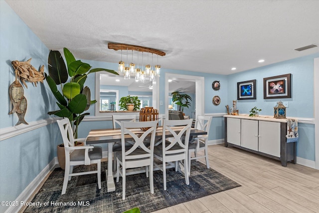 4387 6th Isle Dr, Hernando Beach, FL 34607 - dining room featuring light wood-style floors, a textured ceiling, a chandelier, and baseboards