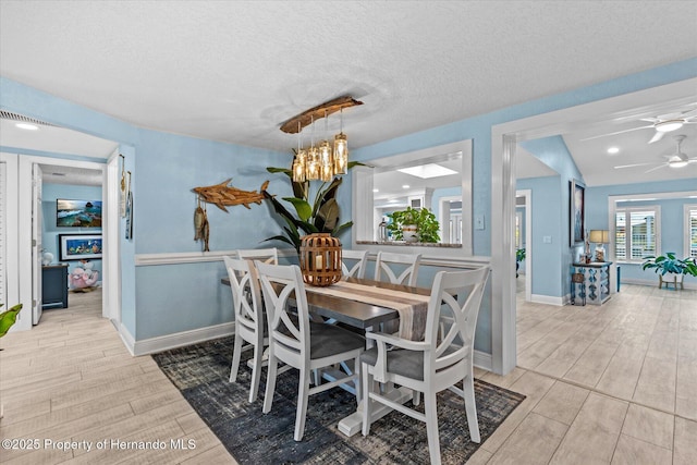 4387 6th Isle Dr, Hernando Beach, FL 34607 - dining room featuring light wood-style floors, a chandelier, a ceiling fan, a textured ceiling, and baseboards