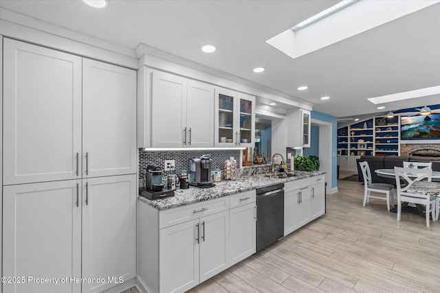 4387 6th Isle Dr, Hernando Beach, FL 34607 - kitchen featuring a skylight, dishwasher, a sink, glass insert cabinets, and white cabinets