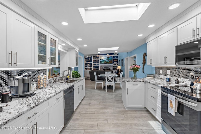 4387 6th Isle Dr, Hernando Beach, FL 34607 - kitchen featuring appliances with stainless steel finishes, a skylight, a sink, white cabinets, and recessed lighting