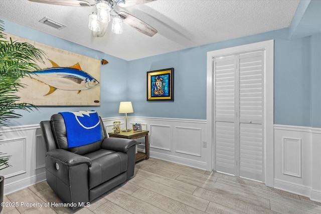 4387 6th Isle Dr, Hernando Beach, FL 34607 - living area featuring ceiling fan, wainscoting, a textured ceiling, and wood finished floors