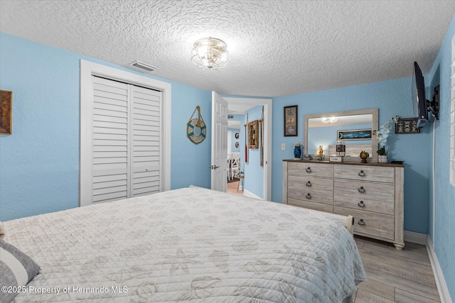 4387 6th Isle Dr, Hernando Beach, FL 34607 - bedroom featuring a textured ceiling, light wood-style floors, baseboards, and a closet