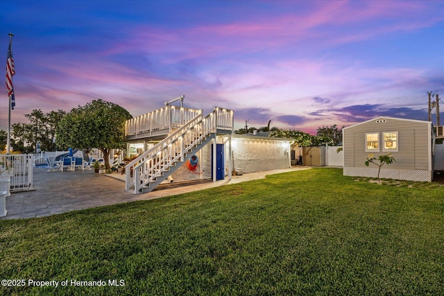 4387 6th Isle Dr, Hernando Beach, FL 34607 - yard at dusk with stairs, a patio, a deck, and a gate