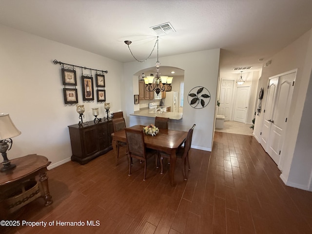 9238 Southern Charm Cir, Brooksville, FL 34613 - dining room featuring a chandelier, arched walkways, dark wood-style floors, and baseboards