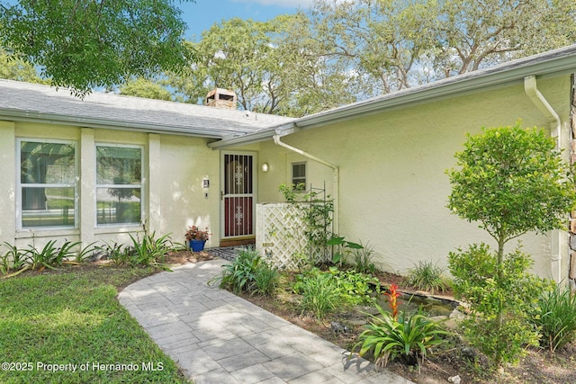 18633 Oak Way Dr, Hudson, FL 34667 - view of exterior entry with stucco siding and a chimney