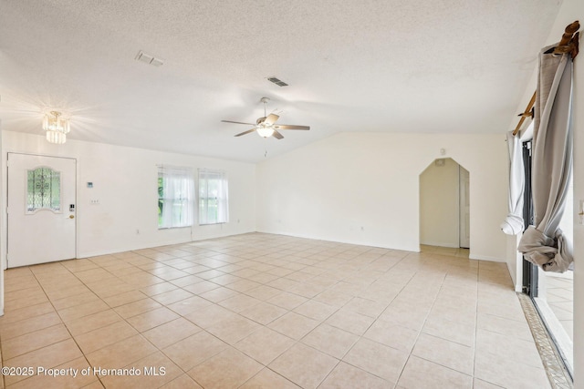 18633 Oak Way Dr, Hudson, FL 34667 - unfurnished living room featuring light tile patterned floors, vaulted ceiling, a ceiling fan, and a textured ceiling