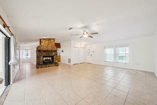18633 Oak Way Dr, Hudson, FL 34667 - unfurnished living room featuring light tile patterned floors, a stone fireplace, ceiling fan, baseboards, and vaulted ceiling
