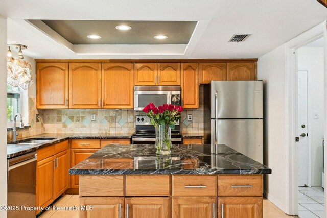 18633 Oak Way Dr, Hudson, FL 34667 - kitchen featuring stainless steel appliances, a sink, a tray ceiling, light tile patterned floors, and decorative backsplash