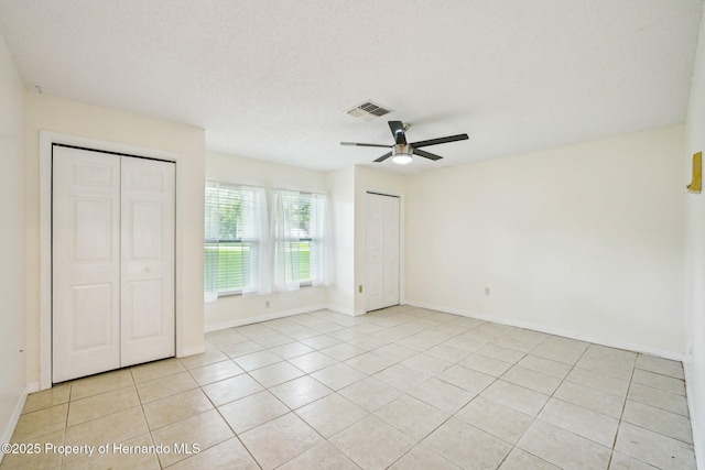18633 Oak Way Dr, Hudson, FL 34667 - unfurnished bedroom with multiple closets, baseboards, light tile patterned floors, and a ceiling fan