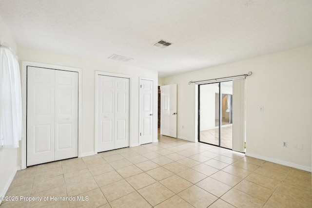 18633 Oak Way Dr, Hudson, FL 34667 - unfurnished bedroom with multiple closets, light tile patterned floors, baseboards, and access to exterior