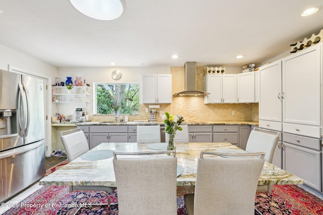 18633 Oak Way Dr, Hudson, FL 34667 - kitchen with stainless steel fridge with ice dispenser, wall chimney range hood, a sink, light stone countertops, and recessed lighting