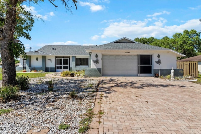 10267 Elgin Blvd, Spring Hill, FL 34608 - ranch-style home featuring a garage, decorative driveway, stucco siding, and roof with shingles
