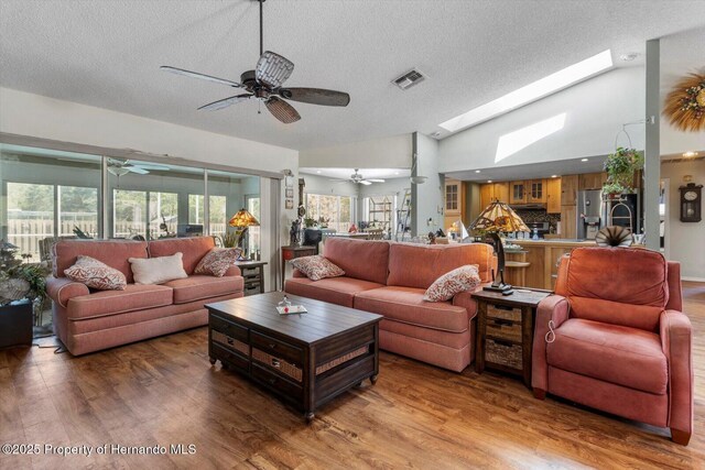 10267 Elgin Blvd, Spring Hill, FL 34608 - living room with ceiling fan, a textured ceiling, wood finished floors, lofted ceiling, and a skylight