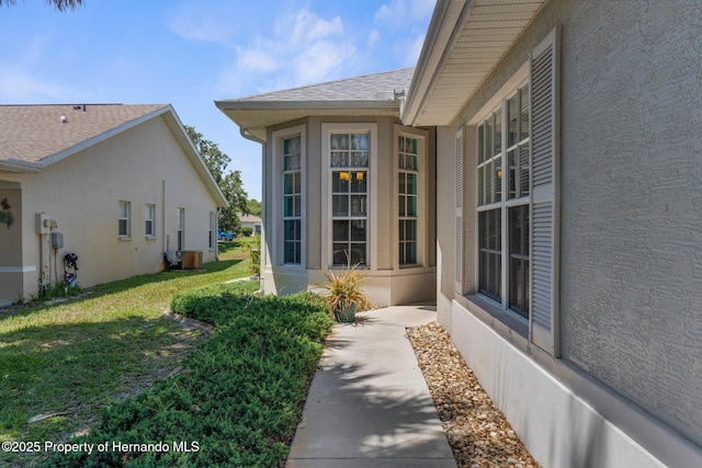 9407 Burnam Dr, Weeki Wachee, FL 34613 - property entrance featuring stucco siding, roof with shingles, and a lawn