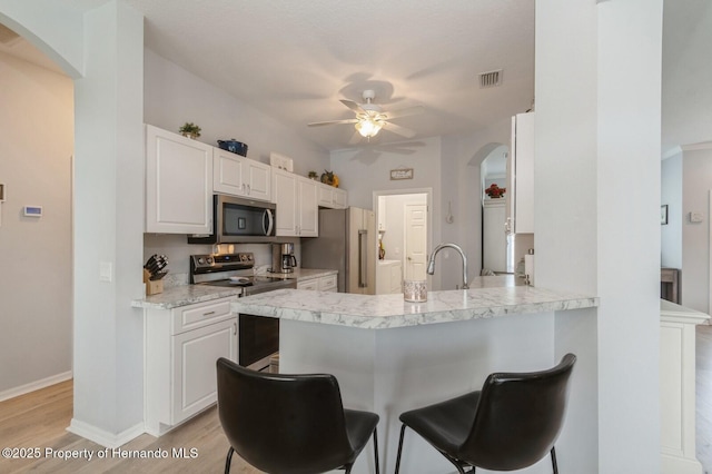 224 W Rexford Dr, Beverly Hills, FL 34465 - kitchen with appliances with stainless steel finishes, a ceiling fan, arched walkways, a kitchen breakfast bar, and light wood-style flooring