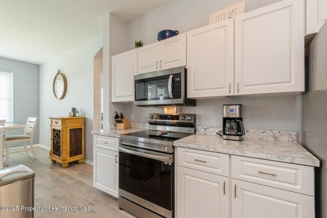 224 W Rexford Dr, Beverly Hills, FL 34465 - kitchen with stainless steel appliances, light wood-type flooring, light countertops, white cabinetry, and baseboards