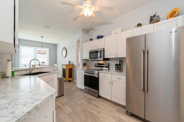 224 W Rexford Dr, Beverly Hills, FL 34465 - kitchen featuring appliances with stainless steel finishes, a sink, white cabinetry, light wood-style floors, and decorative light fixtures