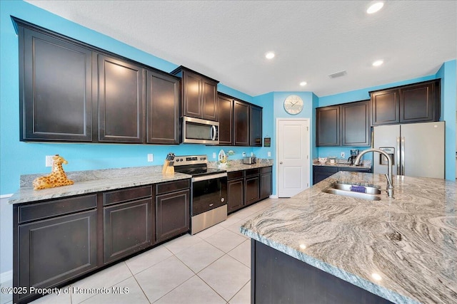 13454 Golden Lime Ave, Spring Hill, FL 34609 - kitchen featuring appliances with stainless steel finishes, a sink, light stone counters, light tile patterned floors, and dark brown cabinetry