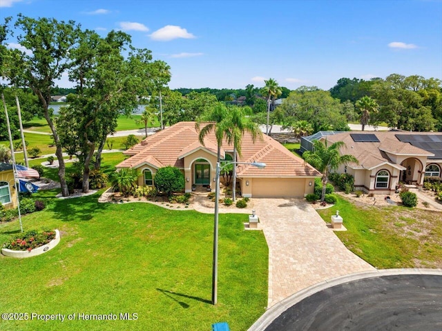 9161 Southern Comfort Ct, Weeki Wachee, FL 34613 - mediterranean / spanish house featuring a garage, driveway, a front lawn, and stucco siding