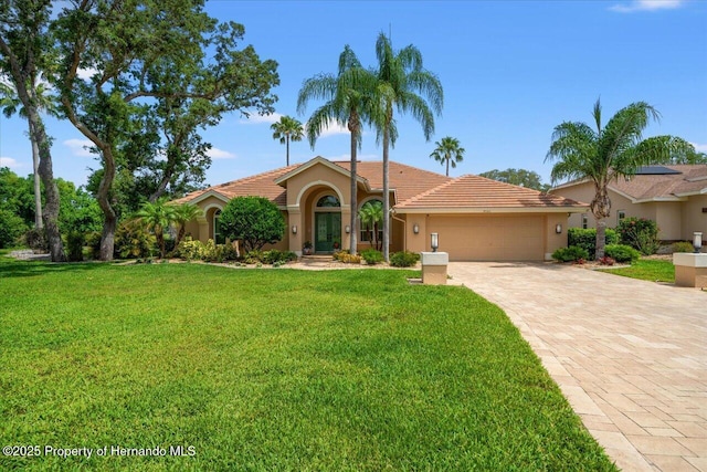 9161 Southern Comfort Ct, Weeki Wachee, FL 34613 - mediterranean / spanish-style home with a garage, a front yard, driveway, and stucco siding