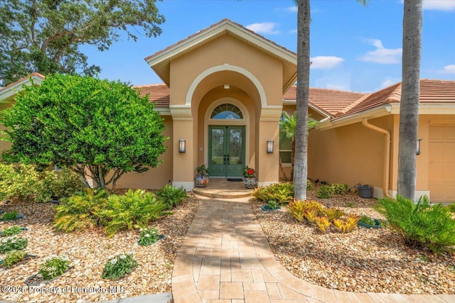 9161 Southern Comfort Ct, Weeki Wachee, FL 34613 - doorway to property featuring french doors, stucco siding, a tile roof, and an attached garage