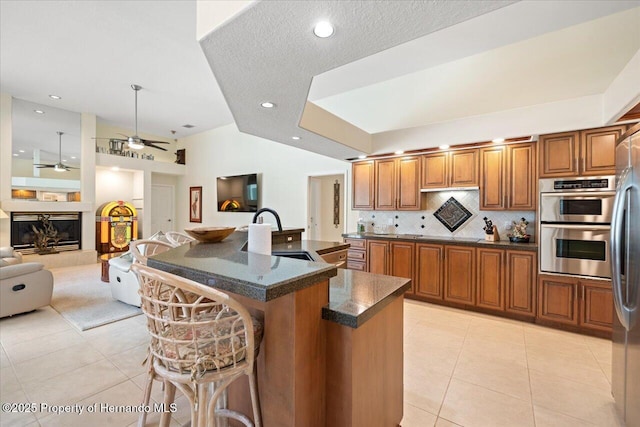 9161 Southern Comfort Ct, Weeki Wachee, FL 34613 - kitchen featuring a sink, light tile patterned floors, brown cabinets, a ceiling fan, and a breakfast bar area
