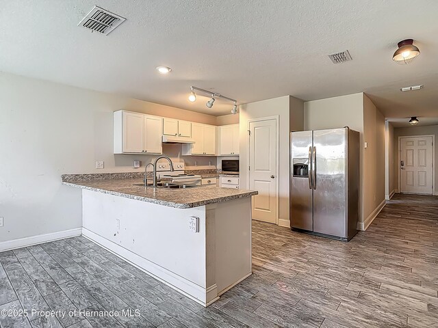 277 Hampshire Ave, Spring Hill, FL 34606 - kitchen with appliances with stainless steel finishes, dark wood-style flooring, a peninsula, a sink, and a textured ceiling