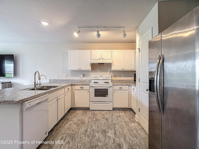 277 Hampshire Ave, Spring Hill, FL 34606 - kitchen with white appliances, a sink, wood finished floors, a peninsula, and white cabinets