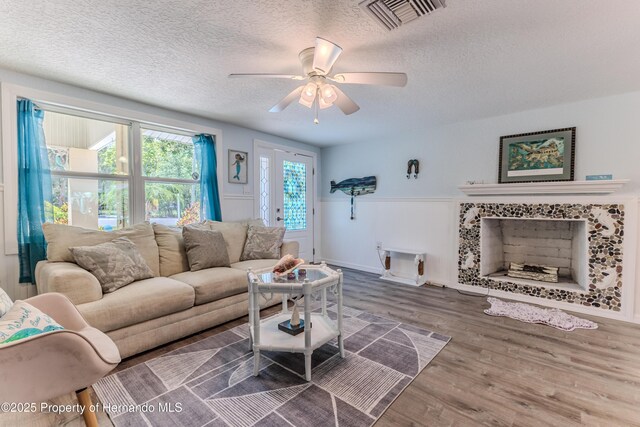 5507 Darlene St, Weeki Wachee, FL 34607 - living room featuring a textured ceiling, wood finished floors, ceiling fan, and a wainscoted wall
