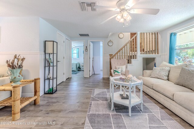 5507 Darlene St, Weeki Wachee, FL 34607 - living area with a textured ceiling, stairs, a ceiling fan, wood finished floors, and a wainscoted wall