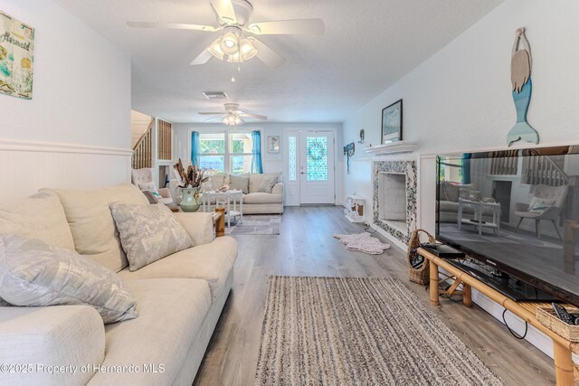 5507 Darlene St, Weeki Wachee, FL 34607 - living room with a ceiling fan, wood finished floors, stairs, a tiled fireplace, and a textured ceiling