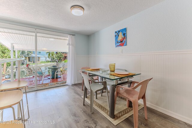 5507 Darlene St, Weeki Wachee, FL 34607 - dining area with wood finished floors, a textured ceiling, and a wainscoted wall