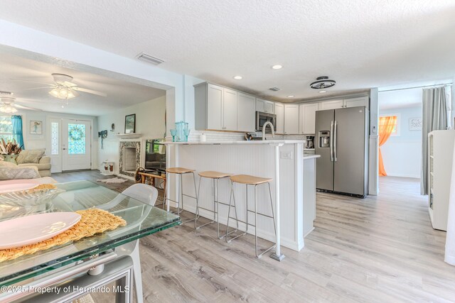 5507 Darlene St, Weeki Wachee, FL 34607 - kitchen with appliances with stainless steel finishes, a peninsula, a breakfast bar, light countertops, and light wood-style floors
